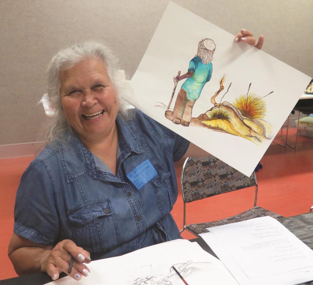A Noongar woman holds up an illustration she has drawn