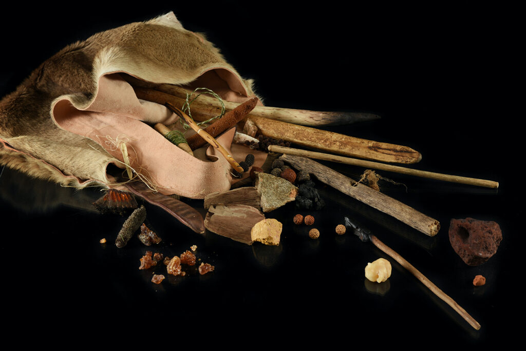 A dilly bag made of kangaroo skin, spilling open to reveal rocks, sticks and tools.