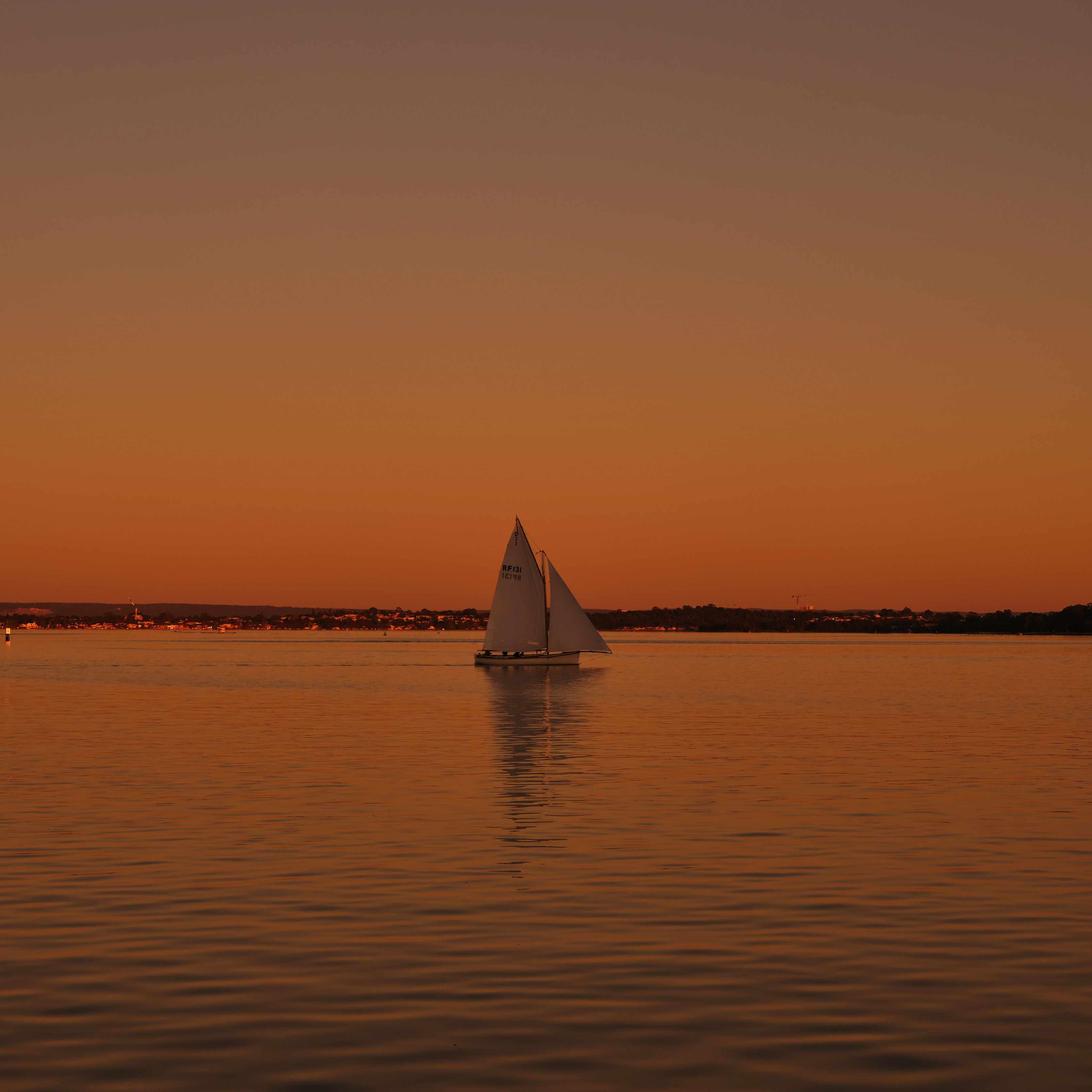 A yacht on a glassy river at sunset