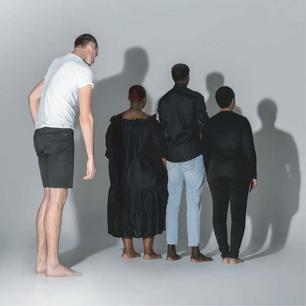 Promotional image from 'stillbirth' part of the Summer Nights curation. Pictured is a tall man who stands behind three other individuals. All individuals have their back to the camera.