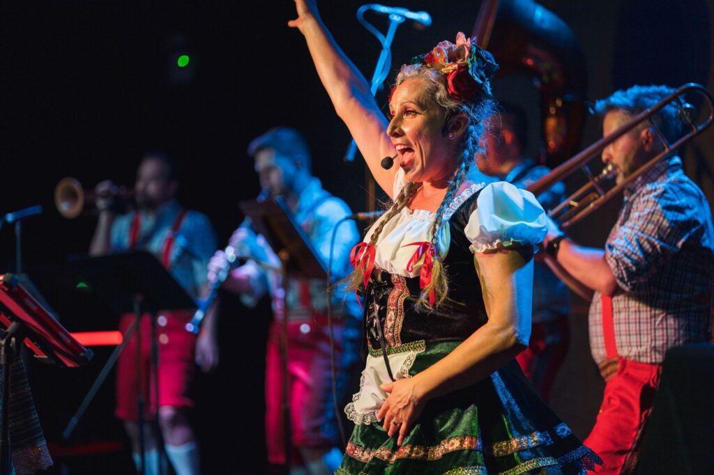 Cream of the crop: A woman in a Bavarian costume dances on stage with men behind her wearing lederhosen and playing brass instruments