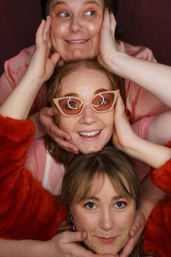 A photo of ALLSTARS trio writers. Pictured is three girls, each with her chin resting on the head of someone below her