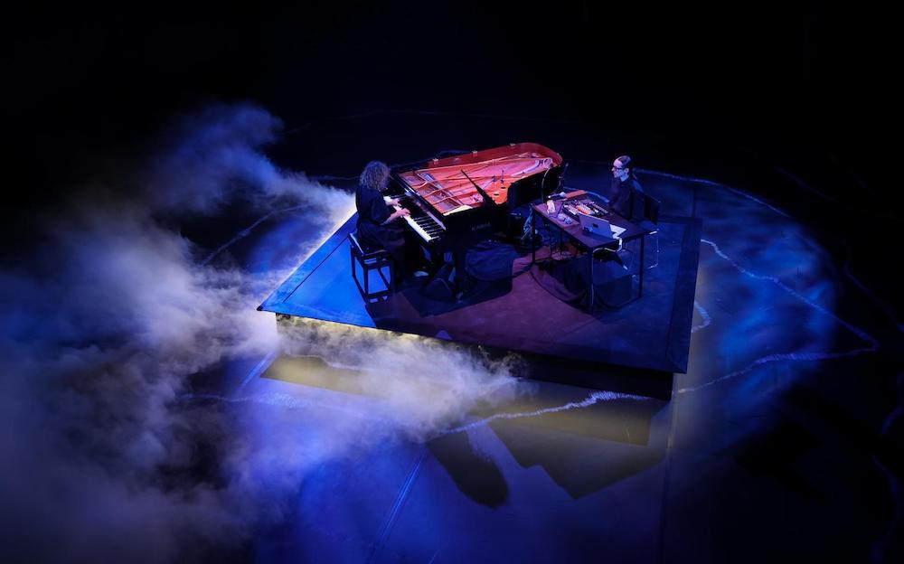 A view from above of a pianist and sound artist on a stage surrounded by smoke