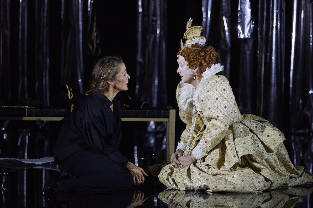 An image from the performance Mary Stuart, pictured is the characters Mary and Elizabeth both kneeling on the floor conversing.