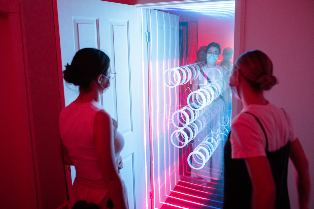 An image from Ta-Ku and friends Songs to Experience, pictured two women admire what appears to be an open door with a mirror that uses intricate light patterns.