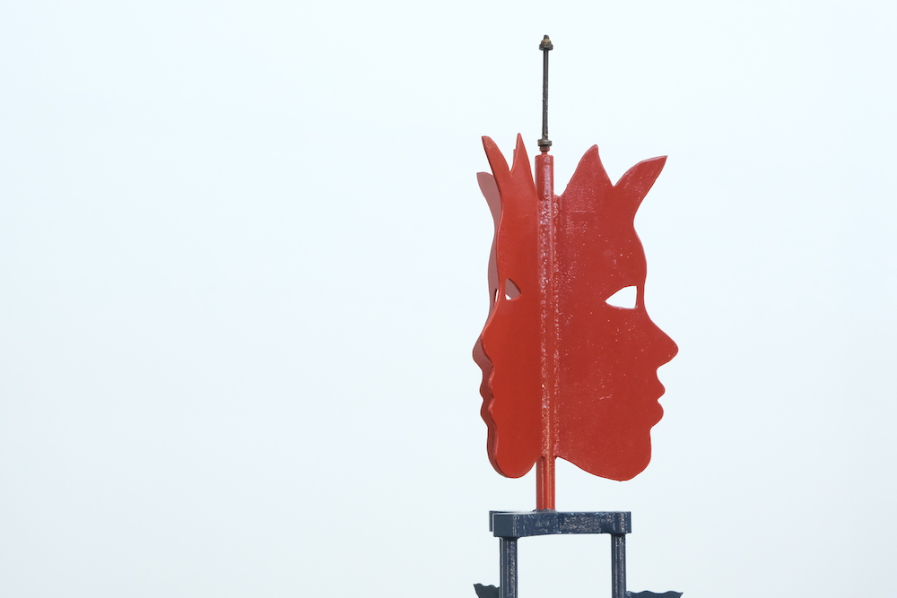 A sculpture from Tony Jones' 'Flying Circus' exhibition. Pictured is a sculpture of a face in metal painted red. 
