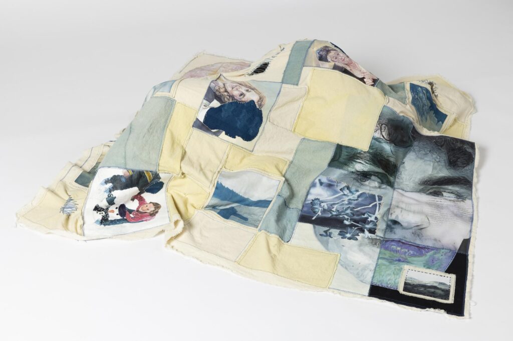 A blanket, made of patches stitched together, some of which are images of faces.