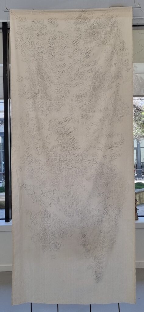 An art work by Nazerul Ben-Dzulkefli comprised of delicate black markings on white cloth.