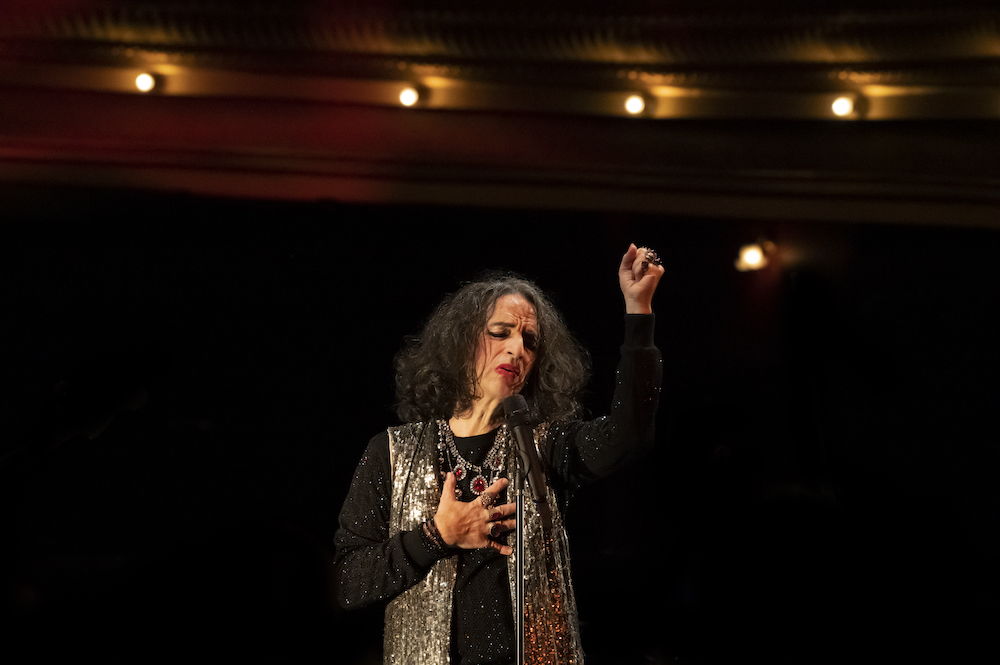 Cabaret festival. A singer holds an arm in the air and the other on her chest. She has her eyes closes in what appears to be an intensely emotional moment 