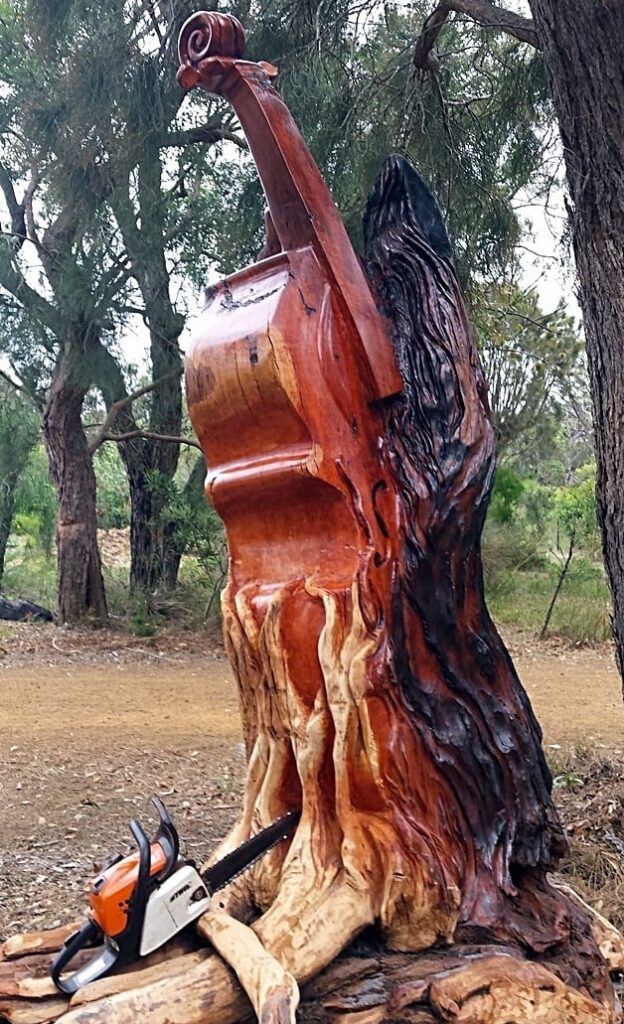 A sculpture of a violin partially engulfed by what looks like tree roots