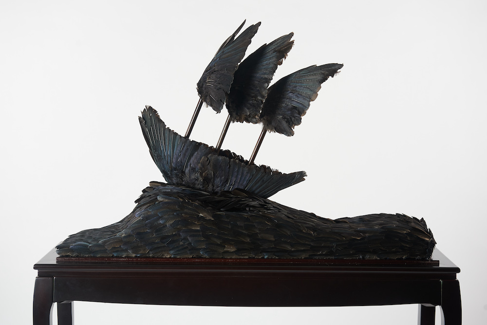 Jasmine Togo-Brisby's 'Passage' is a sculpture of a ship made of black feathers, cresting a feathery wave.