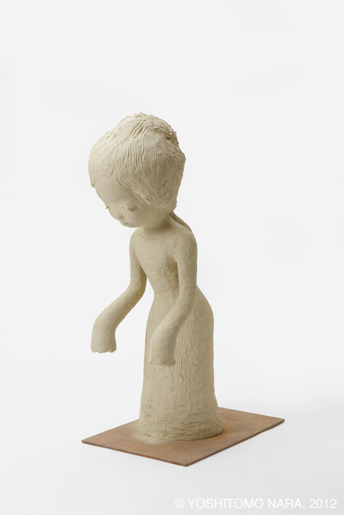 One of Yoshitomo Nara's sculptures of a young girl. Here eyeline is downturned, her arms hang forward as though dejected.