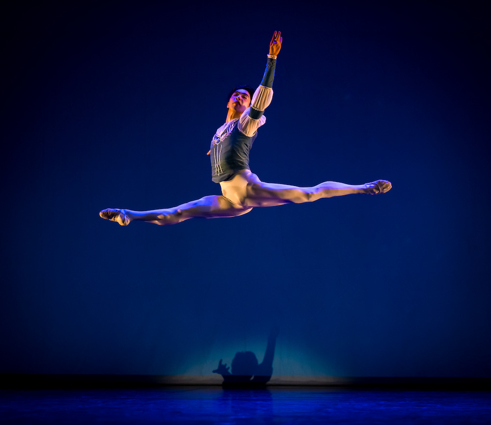 A man mid-way through a grande jete (split leap). His height off the ground is impressive.