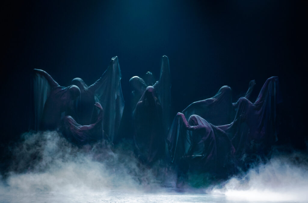 A group of dancers in Slow Haunt are draped in fabric, referencing the Wilis in Giselle. They pose like statues.